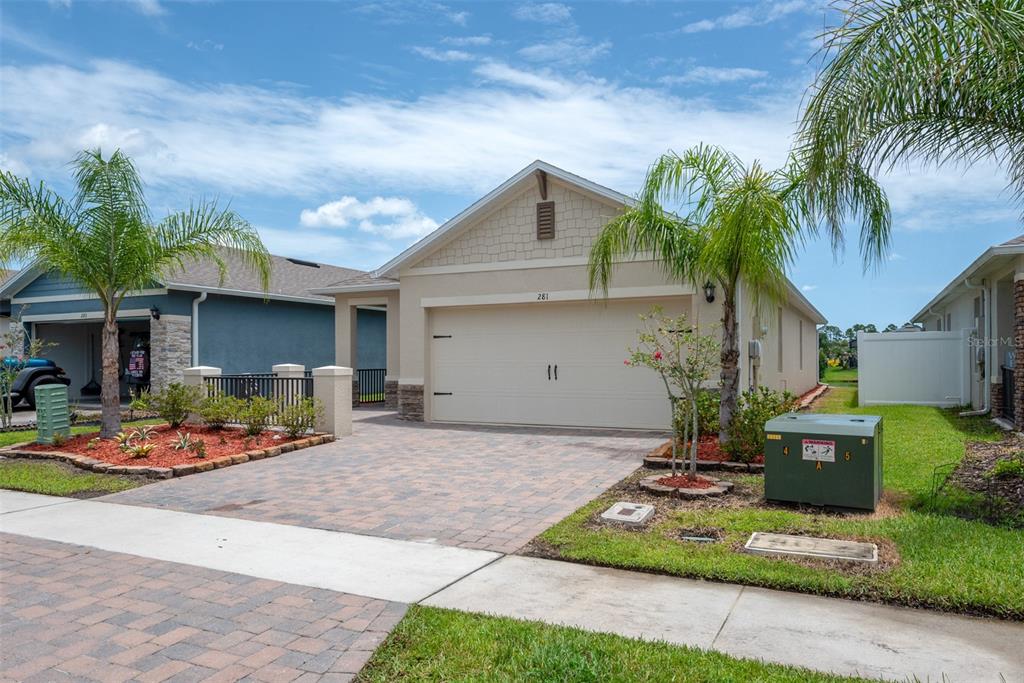 A single-story house with a beige exterior, a two-car garage, and palm trees in front — 281 CARYOTA COURT, NEW SMYRNA BEACH, FL