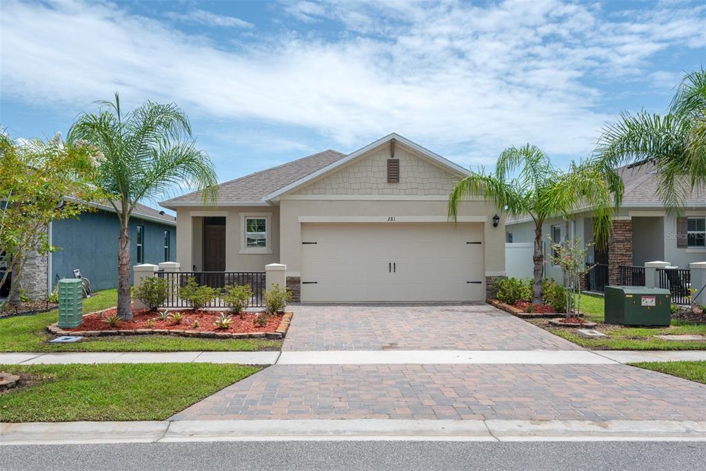 A single-story house with a beige stucco exterior, a two-car garage, and a paved driveway — 281 CARYOTA COURT, NEW SMYRNA BEACH, FL