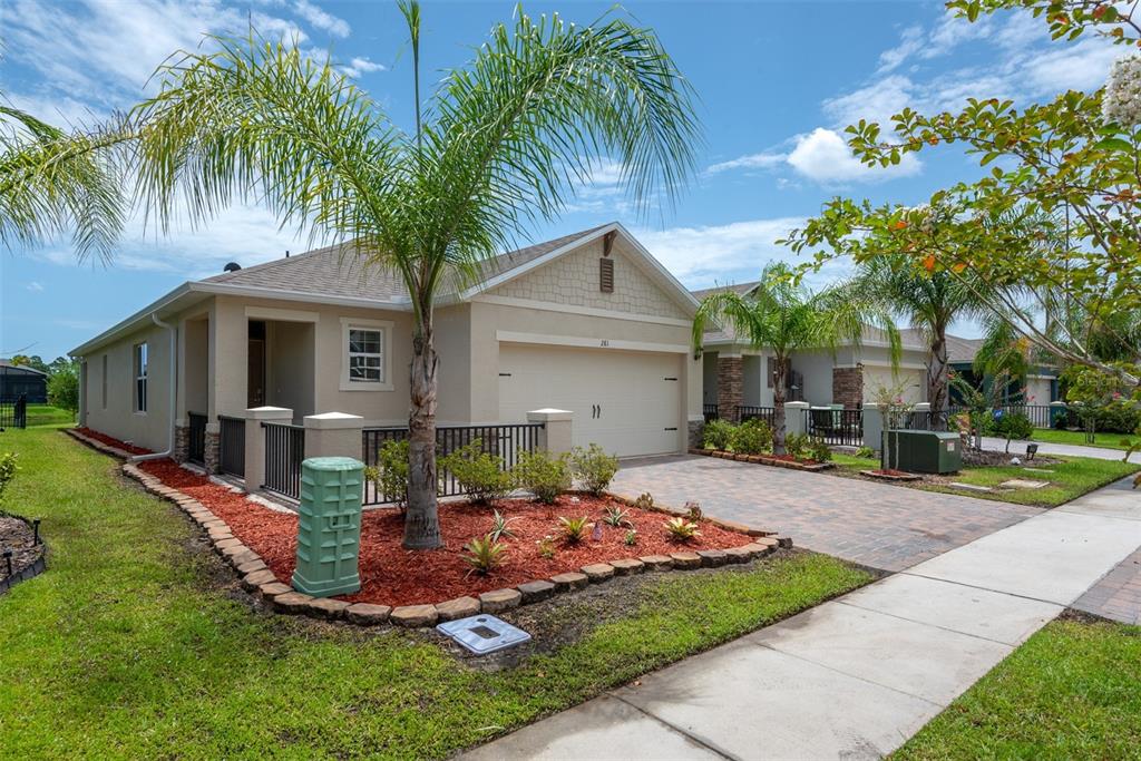 A single-story house with a beige stucco exterior, a two-car garage, and a palm tree — 281 CARYOTA COURT, NEW SMYRNA BEACH, FL