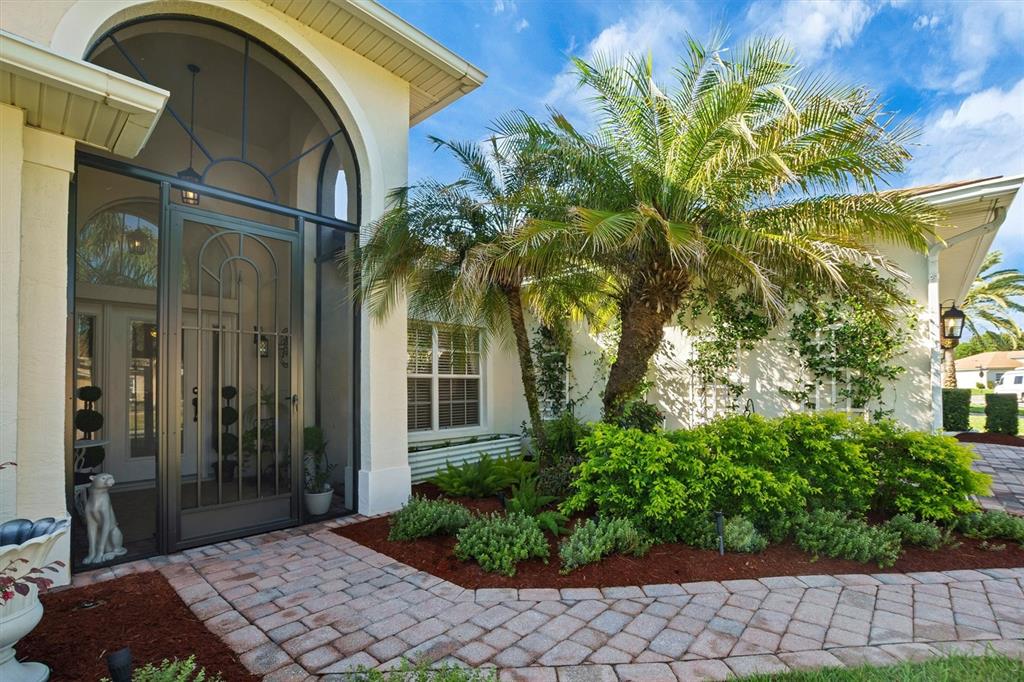 A paved walkway leads to the arched screened entryway of a house with a palm tree — 4315 ASHTON CLUB DRIVE, LAKE WALES, FL
