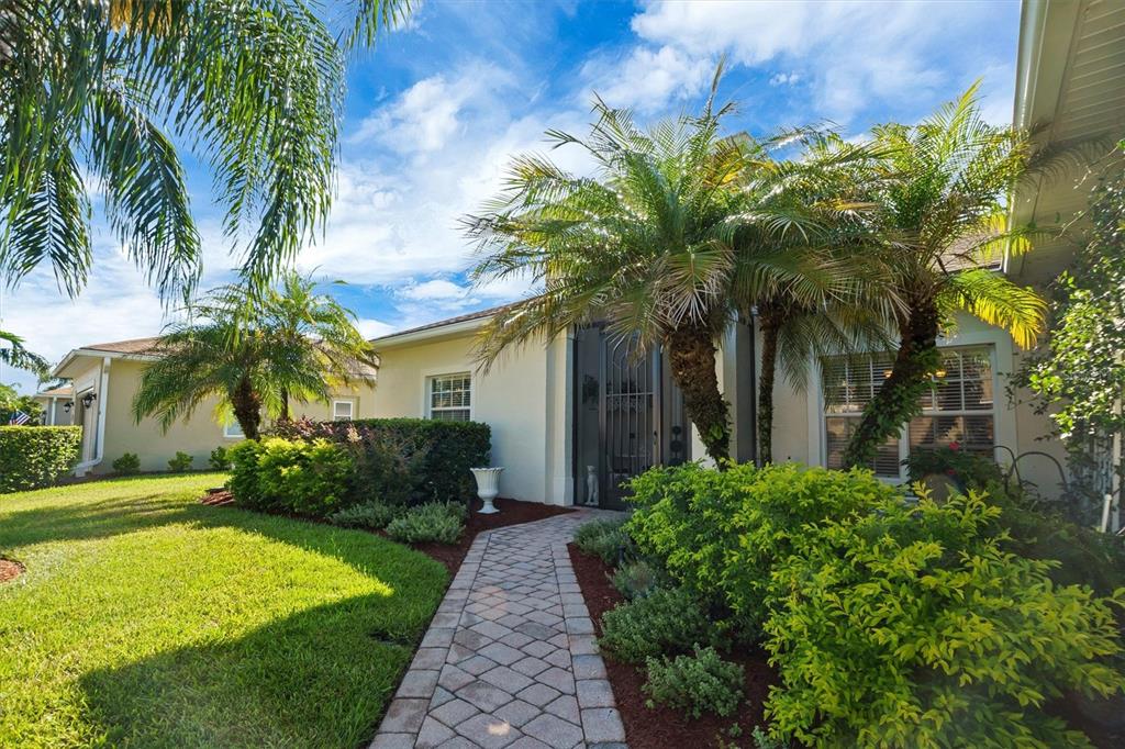 A paved walkway leads to the front entrance of a house surrounded by palm trees — 4315 ASHTON CLUB DRIVE, LAKE WALES, FL