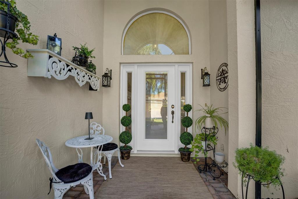 A front entryway features a white door with sidelights, a bistro set, and potted plants — 4315 ASHTON CLUB DRIVE, LAKE WALES, FL