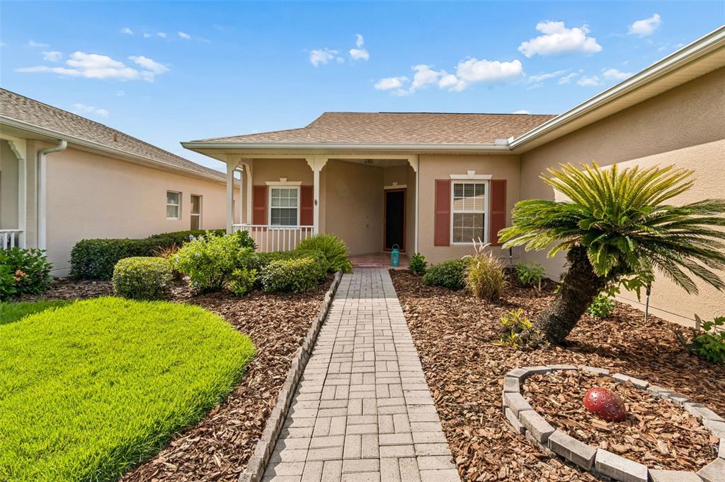 A paved walkway leads to the front entrance of a house with tan stucco siding — 354 ROCK SPRINGS DRIVE, KISSIMMEE, FL