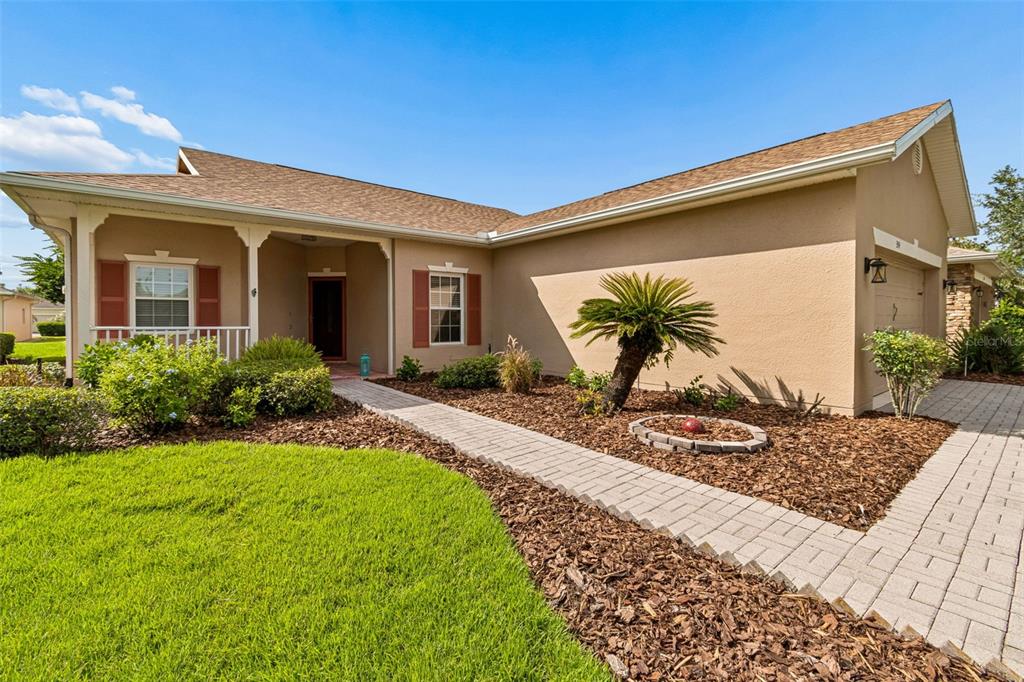 A single-story house with a tan stucco exterior, brown roof, and a paved walkway — 354 ROCK SPRINGS DRIVE, KISSIMMEE, FL