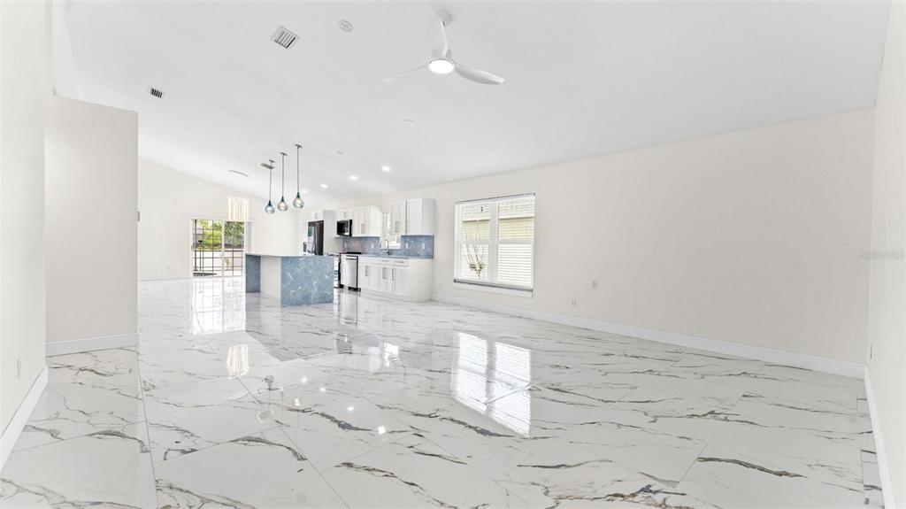 An open-concept kitchen and living area features white marble-look tile flooring and white cabinetry — 11708 CARROLLWOOD COVE DRIVE, TAMPA, FL
