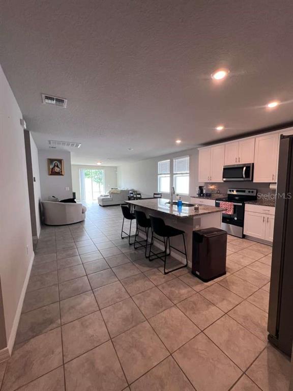 A kitchen with a center island and bar stools opens into a living area — 560 JERRY LN, HAINES CITY, FL