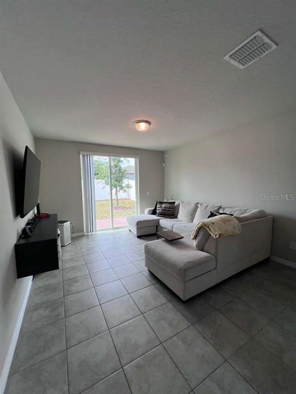 A living room features light gray tile flooring, a sectional sofa, and a sliding glass door — 560 JERRY LN, HAINES CITY, FL