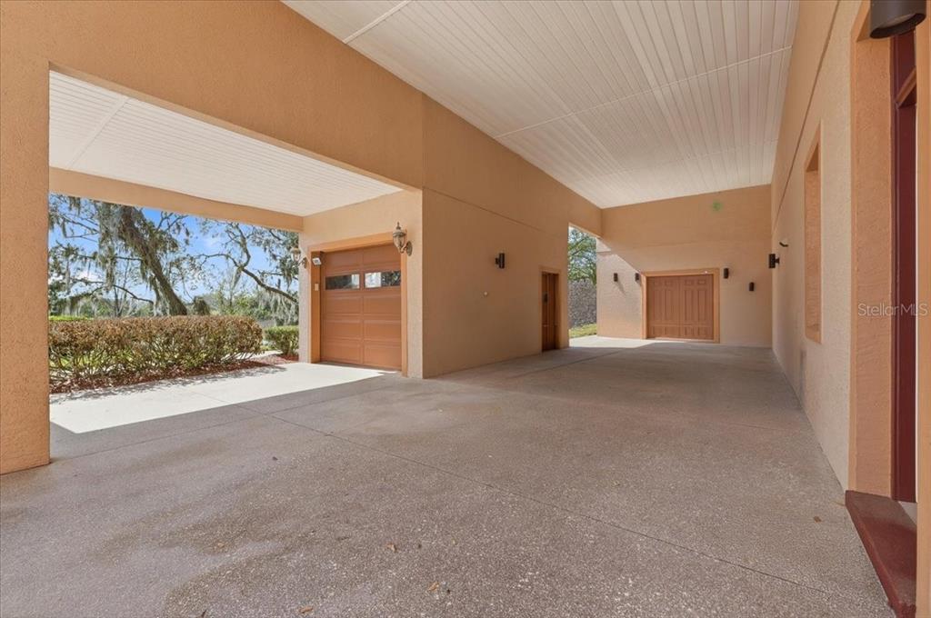 A spacious covered carport features concrete flooring and two separate garage doors — 548 MEANDERING WAY, POLK CITY, FL