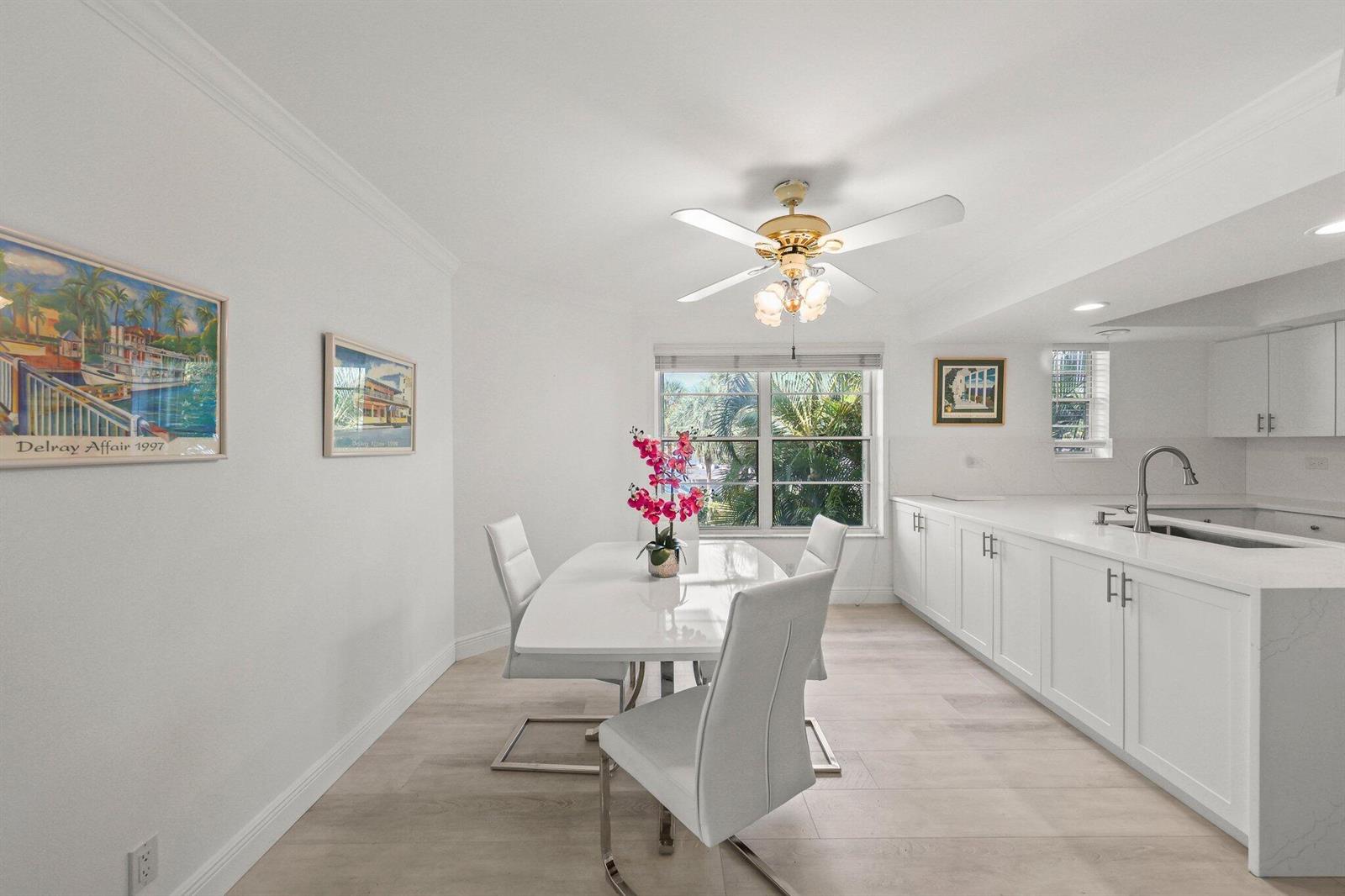A bright dining area features a white table, modern chairs, and an adjacent white kitchen — 664 Forsyth Street # 6, Boca Raton FL 33487, BOCA RATON, FL