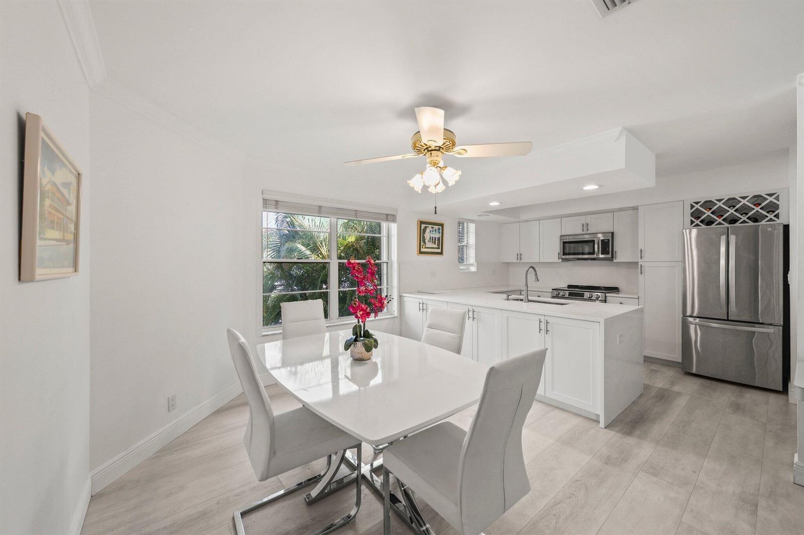 A bright dining area and kitchen featuring white cabinetry, stainless appliances, and light wood flooring — 664 Forsyth Street # 6, Boca Raton FL 33487, BOCA RATON, FL