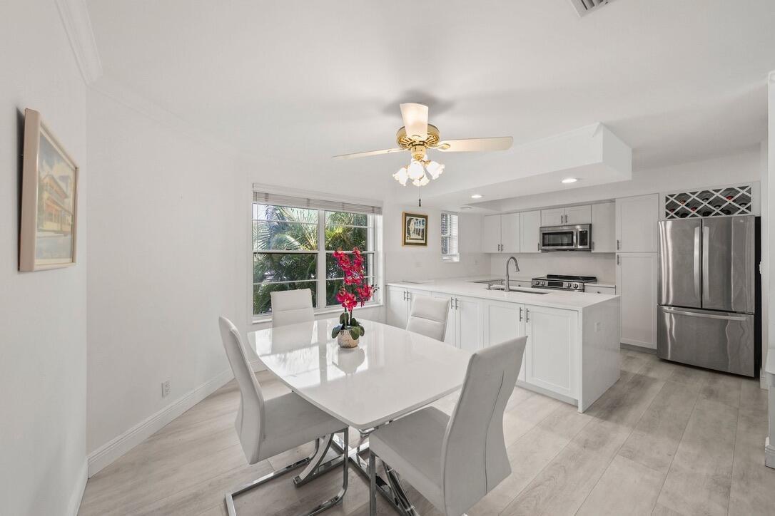 A bright dining area features a white table and chairs adjacent to a modern kitchen — 664 Forsyth Street # 6, Boca Raton FL 33487, BOCA RATON, FL