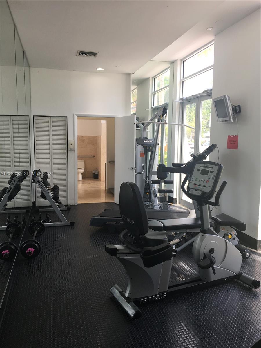 A gym room features a recumbent exercise bike, a weight machine, and a mirrored wall — 200 Ocean Dr # 3C, Miami Beach FL 33139, MIAMI BEACH, FL