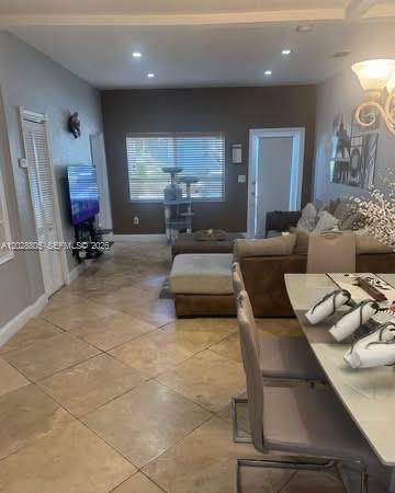A living and dining area features tile flooring, a brown accent wall, and neutral furniture — 6134 SW 22nd St, Miami FL 33155, MIAMI, FL