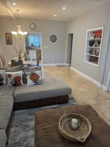 A living room with a gray sectional sofa, tile flooring, and a built-in wall shelf — 6134 SW 22nd St, Miami FL 33155, MIAMI, FL