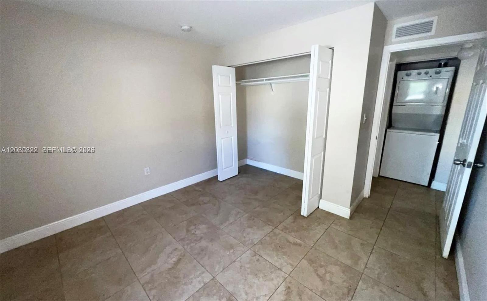 A room with beige walls, tile flooring, an open closet, and an adjacent laundry area — 1999 NW 5th Pl # 2, Miami FL 33136, MIAMI, FL