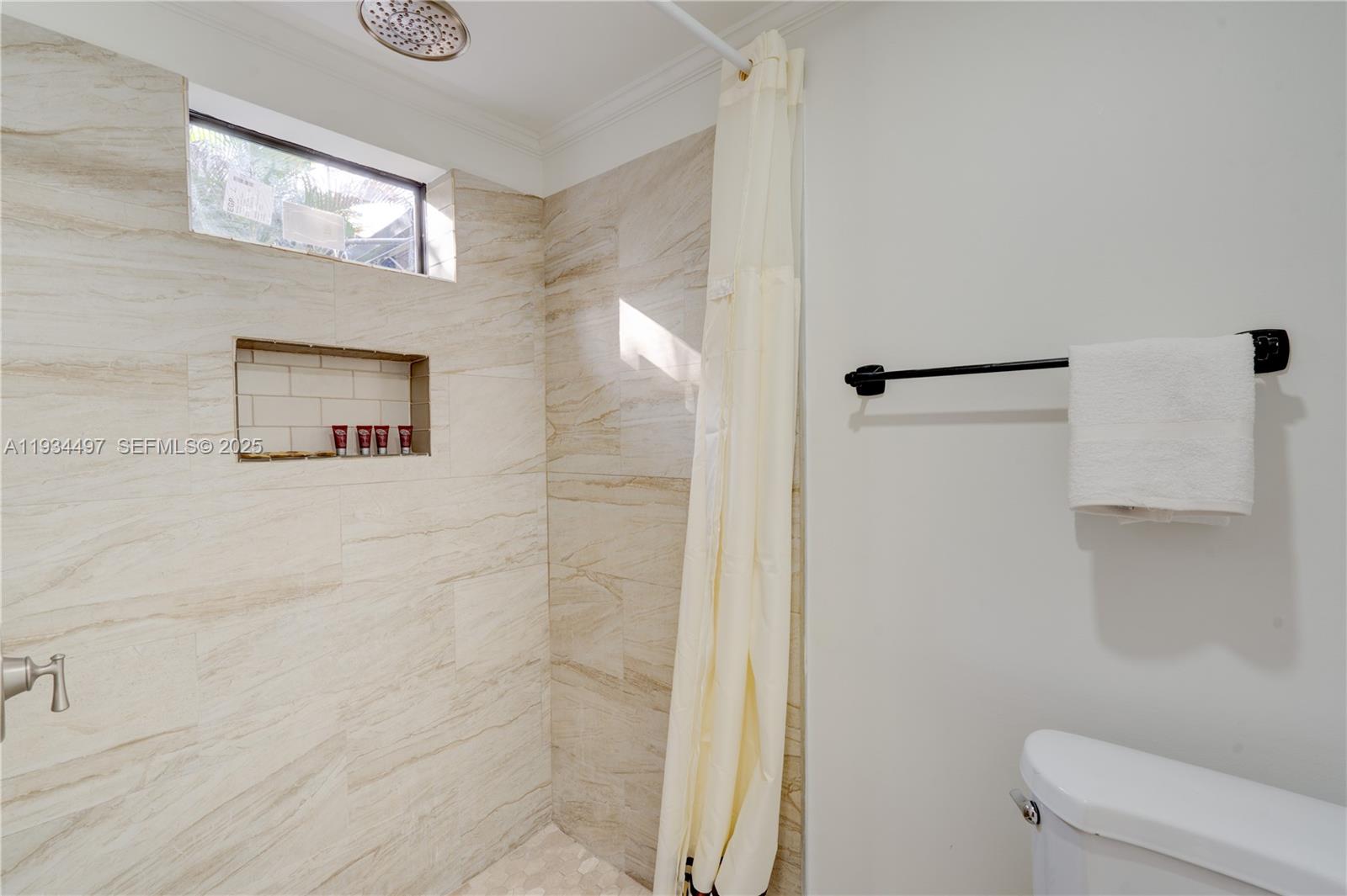 A bathroom features a tiled shower with a niche, a rain showerhead, and a towel rack — 347 NE 110th St, Miami FL 33161, MIAMI, FL