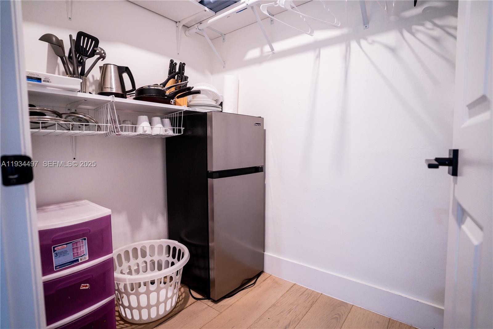 A small closet contains a mini refrigerator, storage shelves with kitchen items, and a laundry basket — 347 NE 110th St, Miami FL 33161, MIAMI, FL