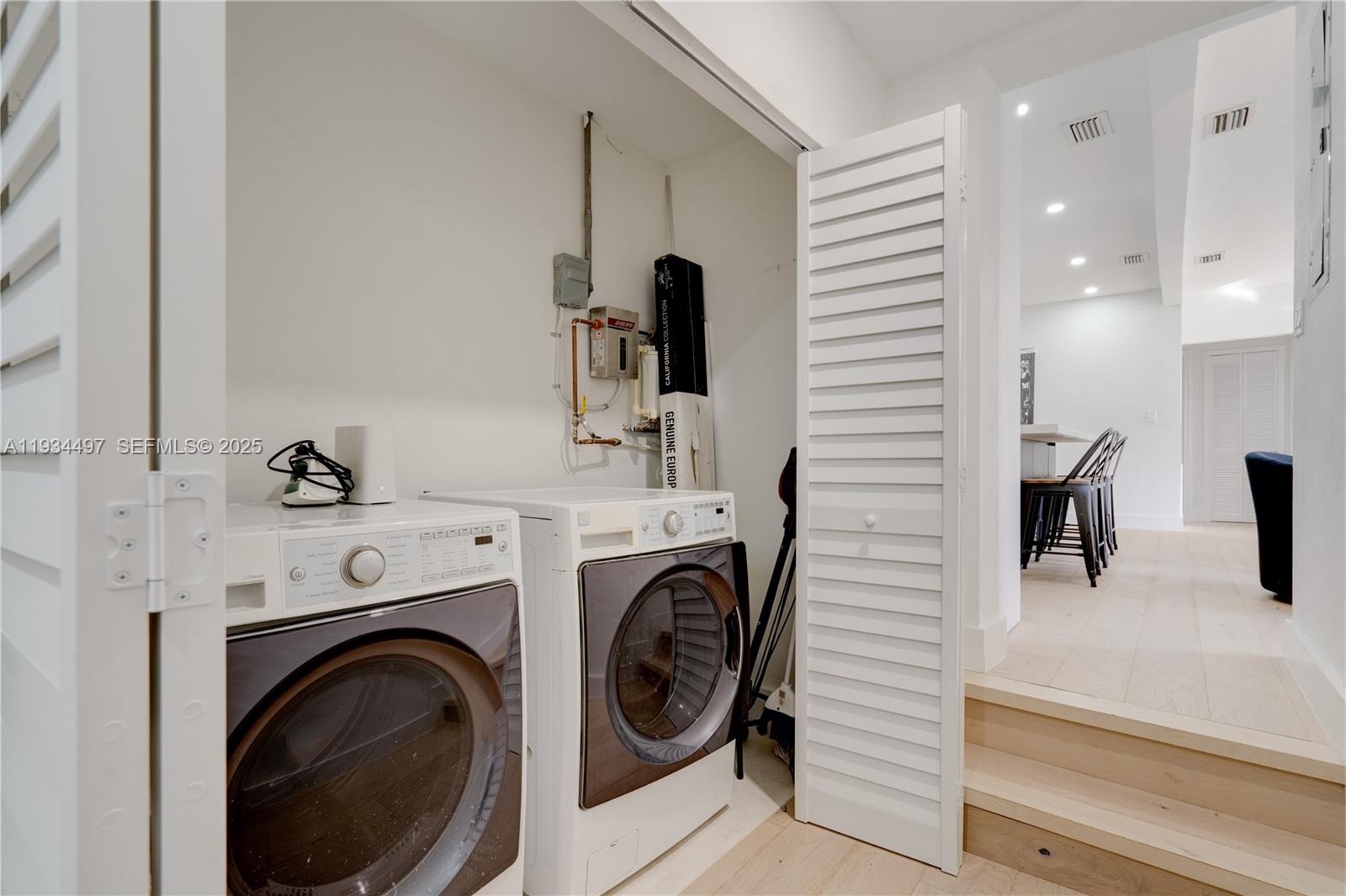 A laundry closet with a washer and dryer sits next to a small staircase — 347 NE 110th St, Miami FL 33161, MIAMI, FL