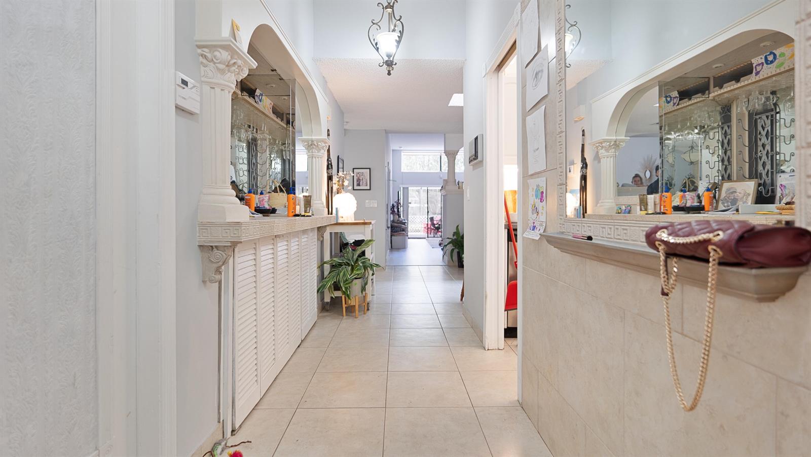 A tiled hallway features mirrored bar areas with decorative columns on both sides — 6680 Canary Palm Circle, Boca Raton FL 33433, BOCA RATON, FL