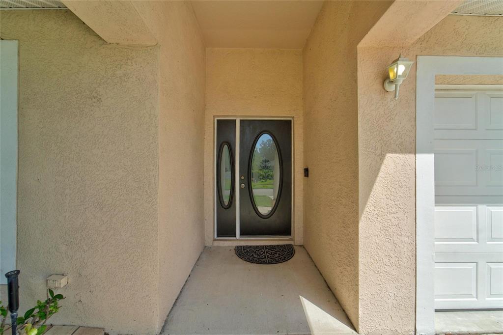 The exterior entryway features a dark front door with a glass oval insert and sidelight — 1514 ORACLE DRIVE, SUN CITY CENTER, FL