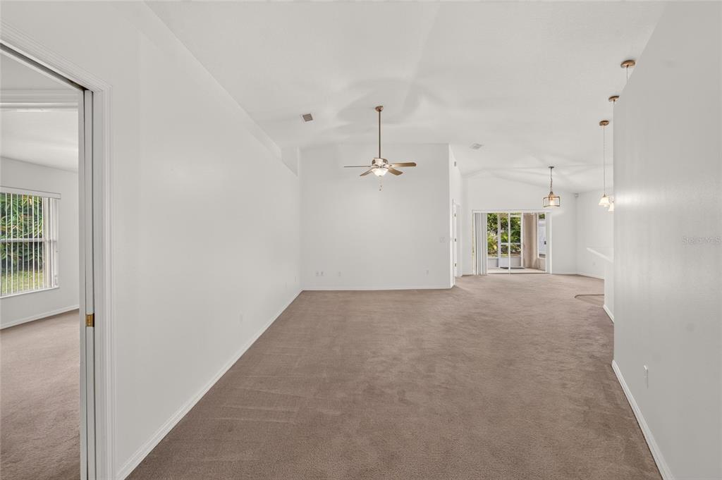 A spacious living area features beige carpeting, white walls, a ceiling fan, and sliding doors — 1514 ORACLE DRIVE, SUN CITY CENTER, FL