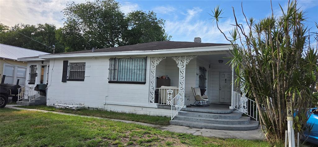 A single-story white house with a front porch, decorative metal supports, and security window bars — 2414 E 8TH AVENUE, TAMPA, FL