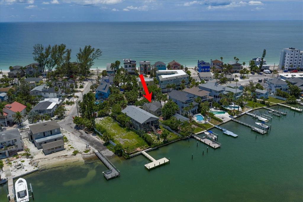An aerial view shows a waterfront house with a private dock on a narrow peninsula — 8405 BAYSHORE DRIVE, TREASURE ISLAND, FL