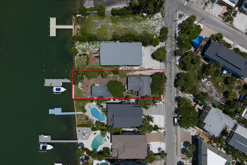 An aerial view shows a waterfront property with two small structures and a private dock — 8405 BAYSHORE DRIVE, TREASURE ISLAND, FL