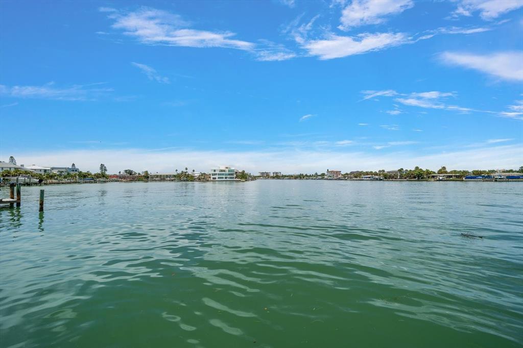A view of a calm waterway with houses along the distant shoreline under a blue sky — 8405 BAYSHORE DRIVE, TREASURE ISLAND, FL