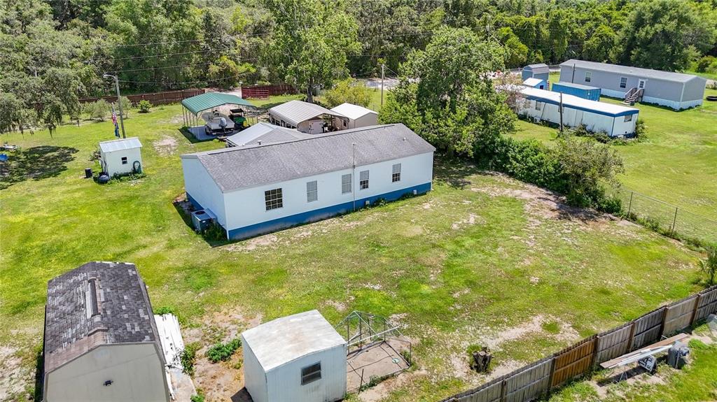 An aerial view shows a mobile home with several outbuildings and sheds on a grassy lot — 9801 UPLAND DRIVE, HUDSON, FL