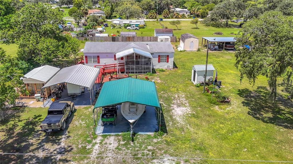 An aerial view shows a house with a screened porch, multiple carports, and a boat — 9801 UPLAND DRIVE, HUDSON, FL