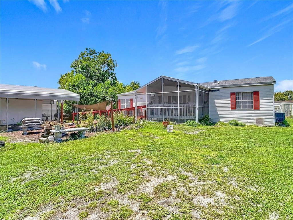 A backyard view of a house with a screened-in porch and an attached carport — 9801 UPLAND DRIVE, HUDSON, FL