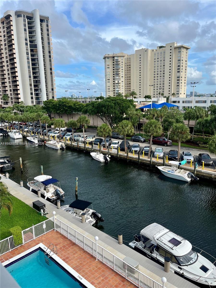 An elevated view shows a canal with docked boats, a swimming pool, and high-rise buildings — 1650 NE 115th St # 507, Miami FL 33181, MIAMI, FL