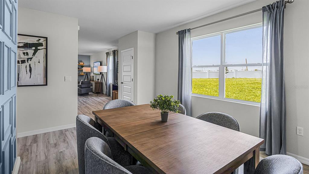 A dining room features a wooden table, gray chairs, and a window overlooking a field — 6163 CORONARI LANE, WINTER HAVEN, FL