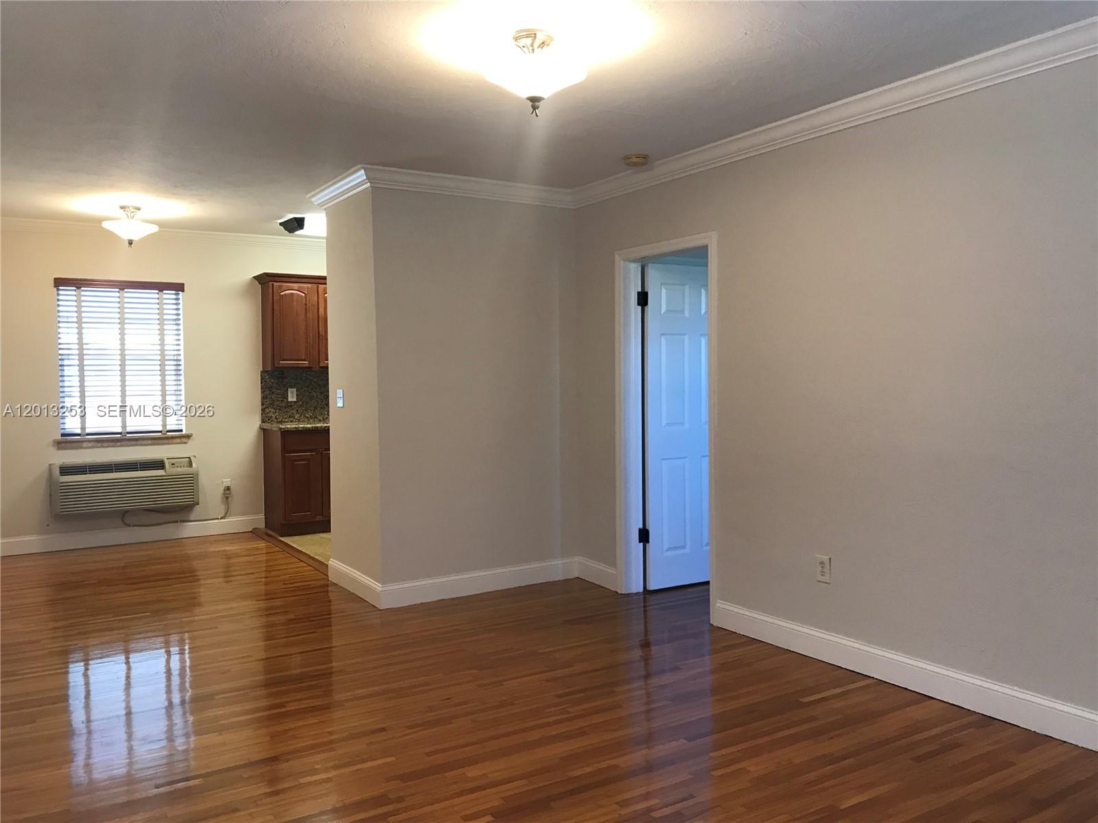A room with hardwood floors, a doorway, and a view into a kitchen area — 35 Antilla Ave # 2, Coral Gables FL 33134, CORAL GABLES, FL