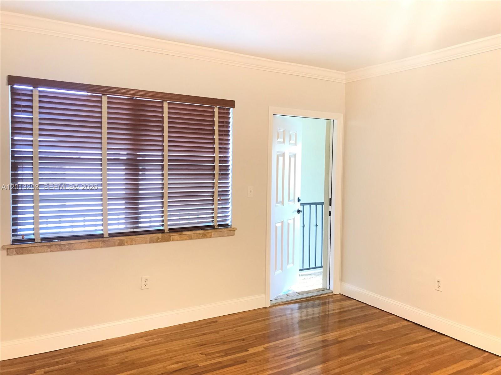 A room with hardwood floors, a window with wooden blinds, and an open doorway — 35 Antilla Ave # 2, Coral Gables FL 33134, CORAL GABLES, FL