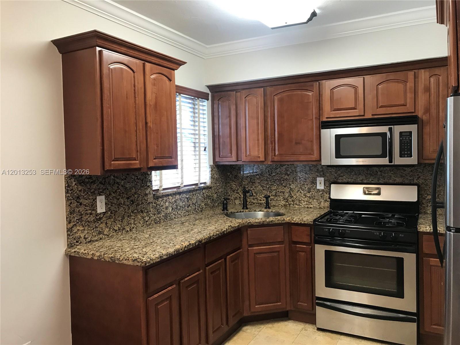 A kitchen features dark wood cabinets, granite countertops, and stainless steel appliances — 35 Antilla Ave # 2, Coral Gables FL 33134, CORAL GABLES, FL