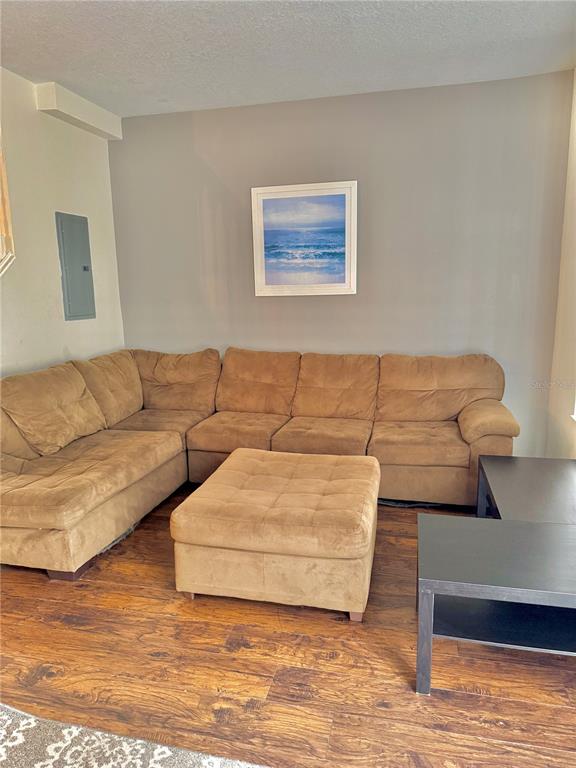 A living room features a large brown sectional sofa, a matching ottoman, and hardwood floors — 1150 S BEACH CIRCLE, KISSIMMEE, FL