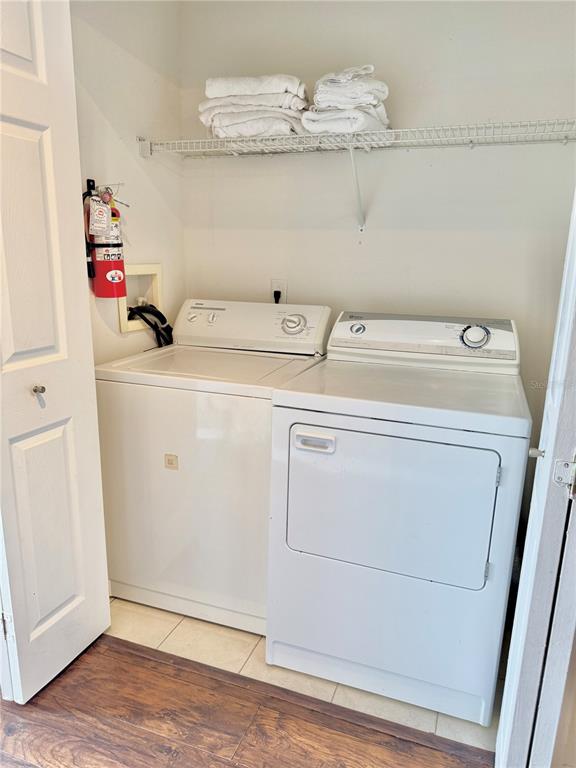 A laundry closet contains a white top-loading washing machine and a dryer beneath a shelf — 1150 S BEACH CIRCLE, KISSIMMEE, FL