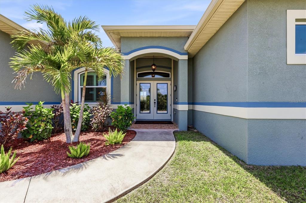 The exterior of a house features a concrete walkway leading to a double front door — 15610 SEAFOAM CIRCLE, PORT CHARLOTTE, FL