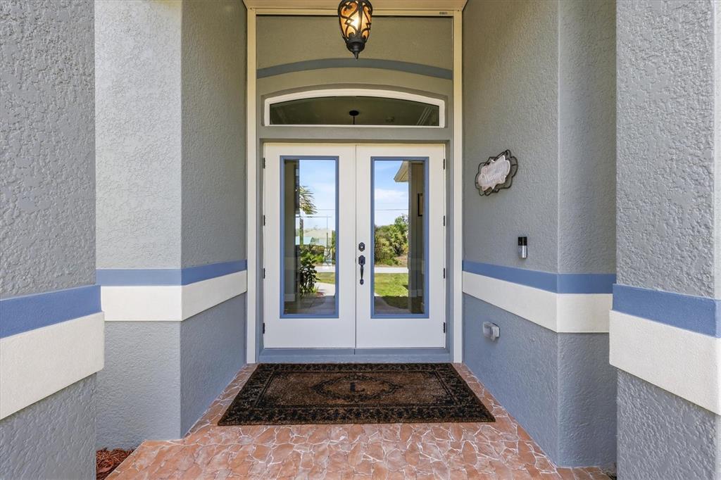A front entryway features double glass doors, a stone floor, and gray stucco walls — 15610 SEAFOAM CIRCLE, PORT CHARLOTTE, FL