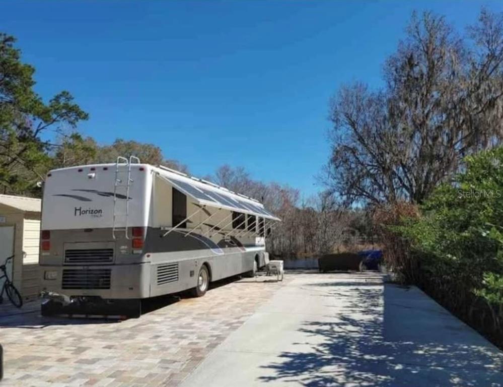 A large recreational vehicle is parked on a paved driveway next to a small shed — 2092 CULBREATH ROAD UNIT A78, BROOKSVILLE, FL