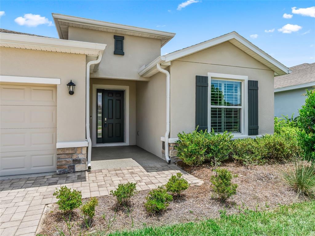 A single-story house exterior features a beige stucco facade, a stone base, and a garage — 5208 NW 46TH LANE ROAD, OCALA, FL