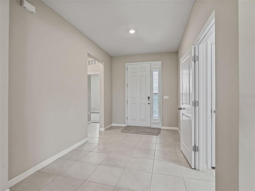 An entryway features light-colored tile flooring, a white front door, and a nearby doorway — 5208 NW 46TH LANE ROAD, OCALA, FL