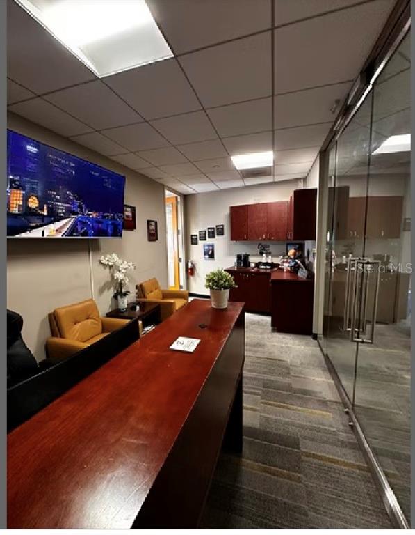 An office break room features a long wooden counter, tan armchairs, and dark cabinetry — 400 N ASHLEY DRIVE UNIT 2050, TAMPA, FL