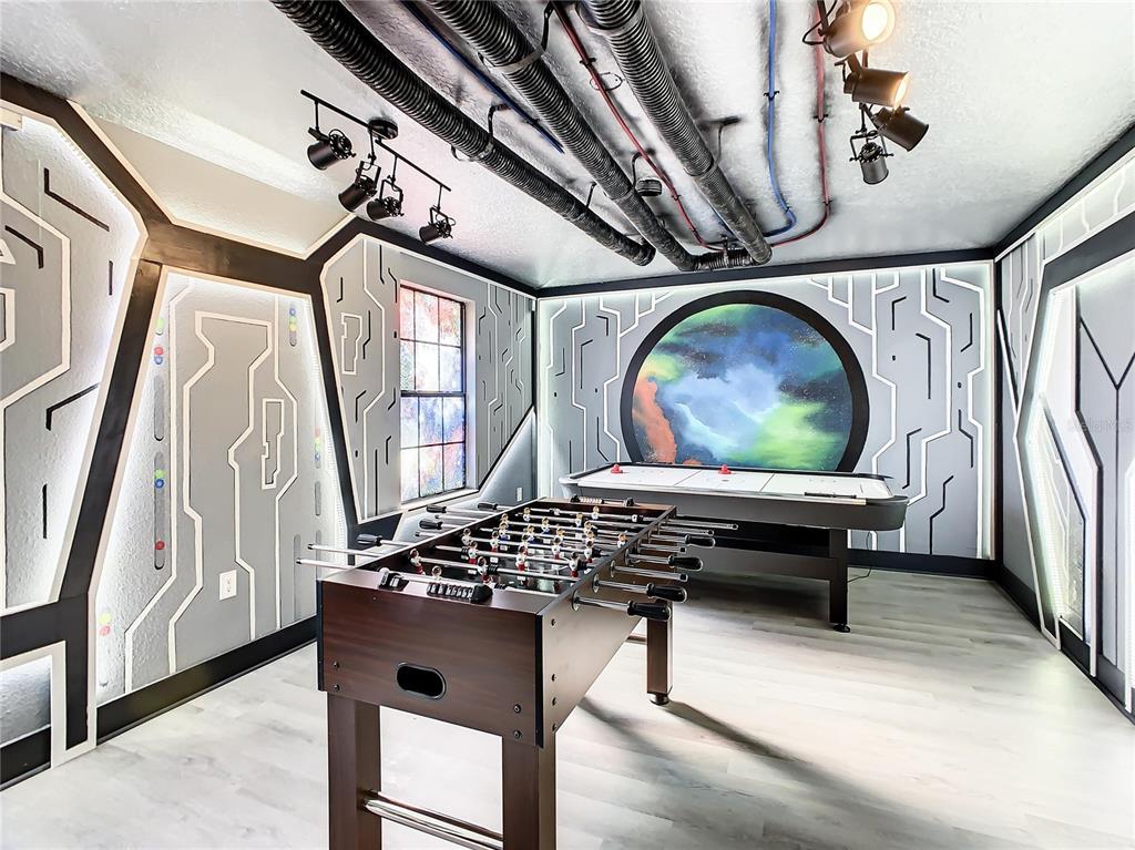 A game room features a foosball table, air hockey table, and sci-fi themed wall decor — 9155 CADDIE WAY, DAVENPORT, FL