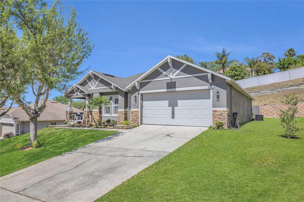 A single-story house with a gray stucco exterior, stone accents, and a two-car garage — 1510 PIER STREET, CLERMONT, FL