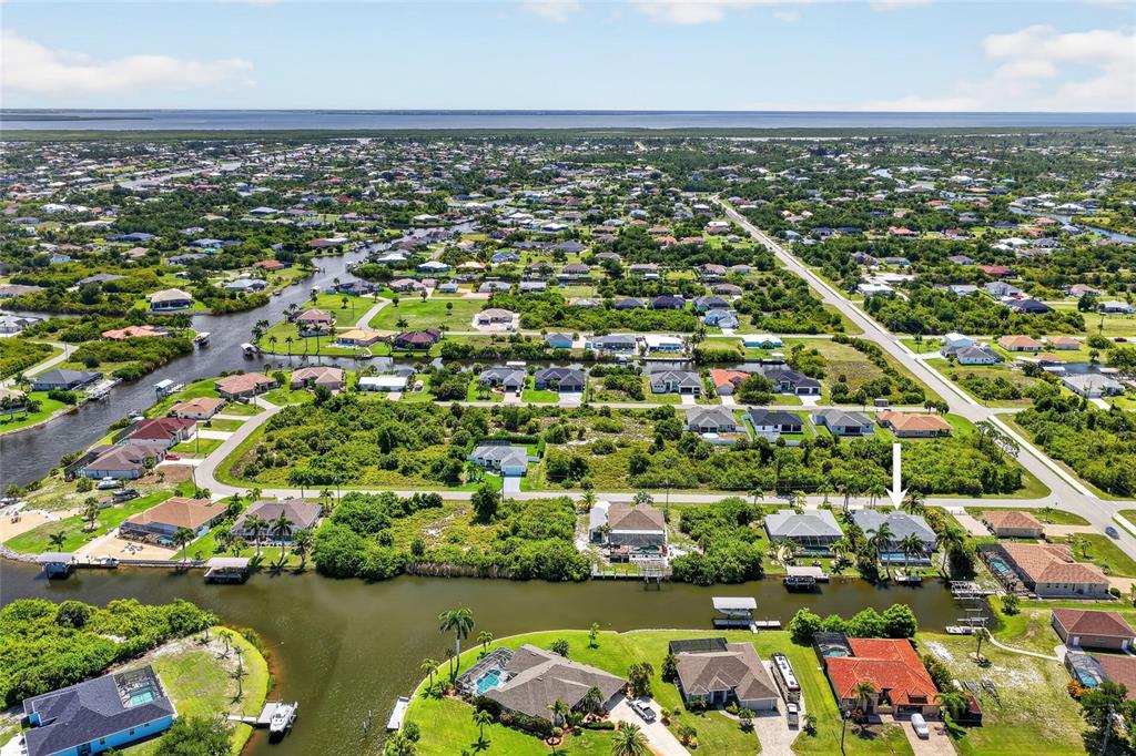 Aerial view of a suburban neighborhood with houses along a canal, featuring a marked property — 9276 MIAMI CIRCLE, PORT CHARLOTTE, FL