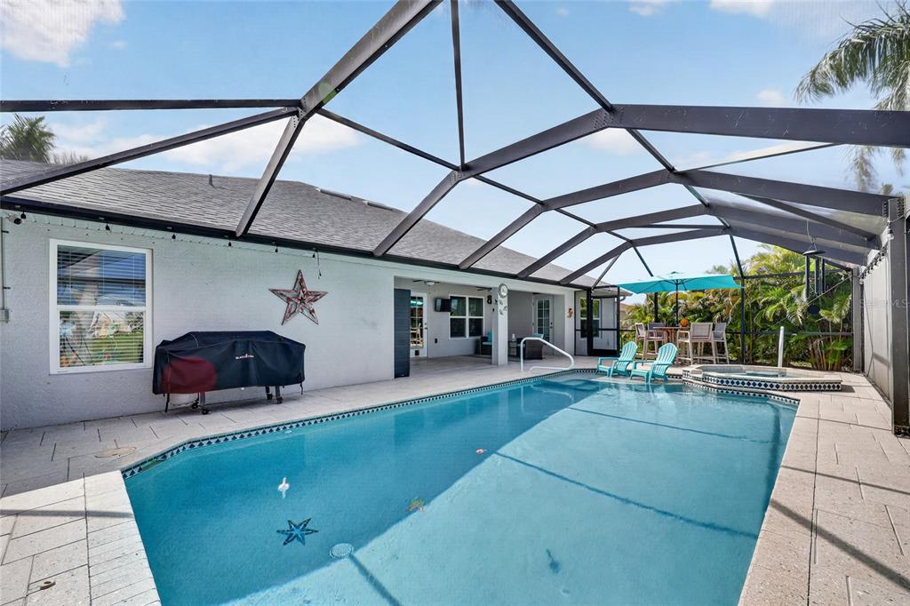A screened-in swimming pool and hot tub area with a patio and outdoor seating — 9276 MIAMI CIRCLE, PORT CHARLOTTE, FL
