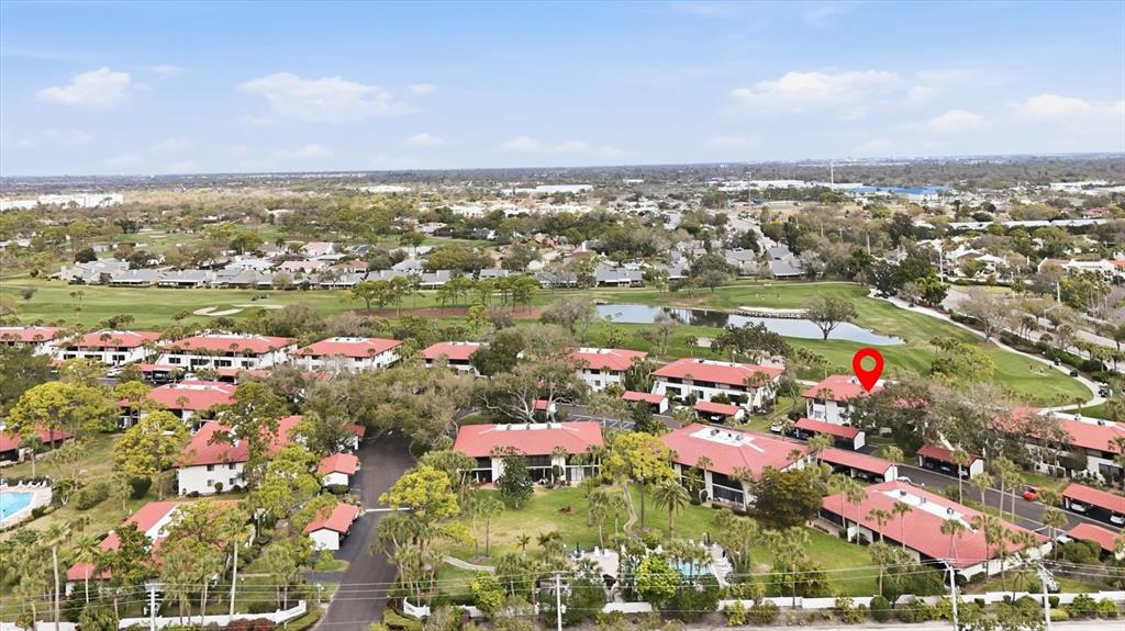 An aerial view shows a residential complex with red-roofed buildings surrounded by a golf course — 3500 EL CONQUISTADOR PARKWAY UNIT 144, BRADENTON, FL